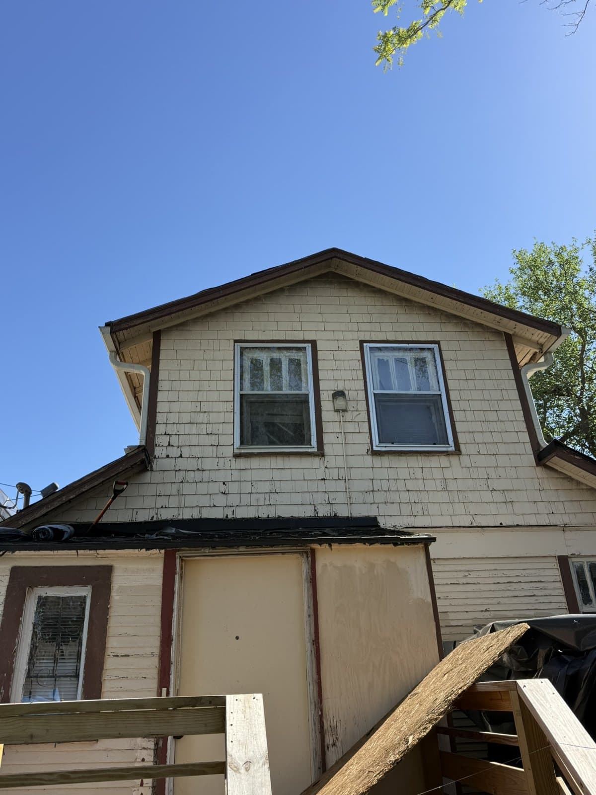 Rear gable above a lower addition, with a wooden deck beside the work area
