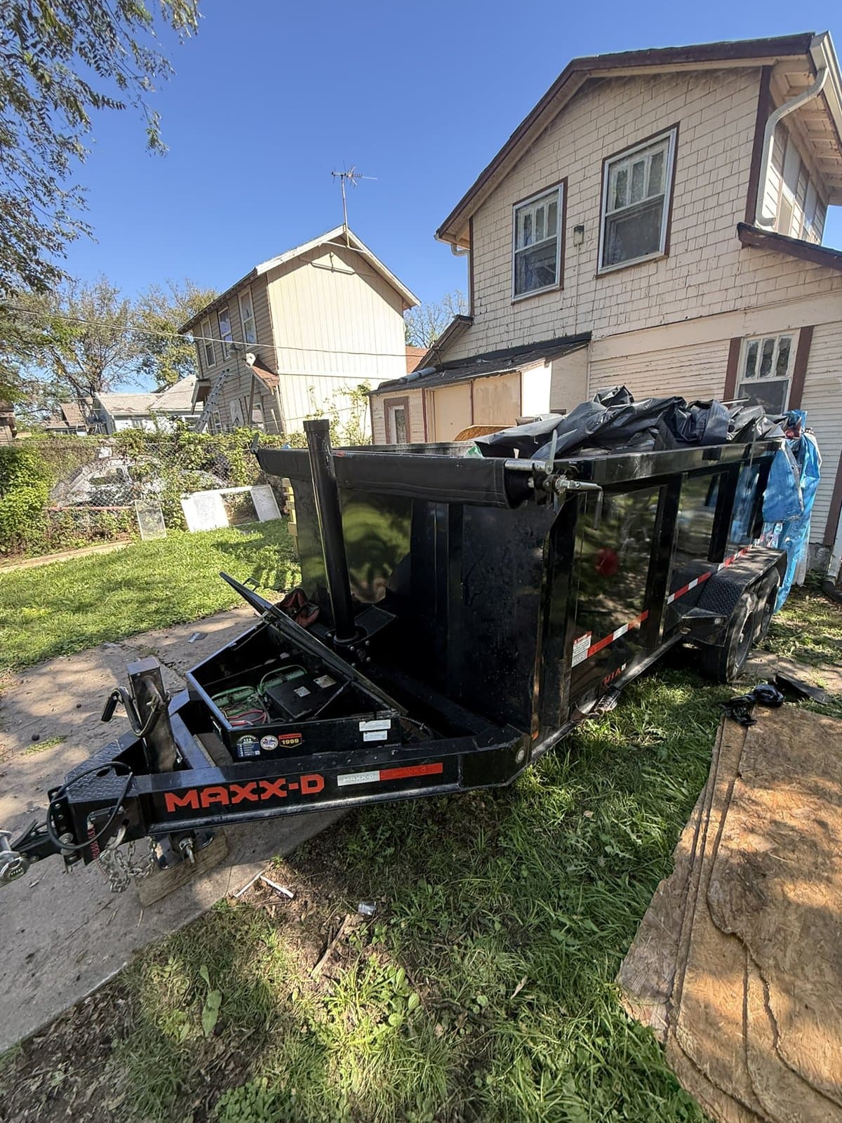 A loaded debris trailer next to the rear deck of a Kansas City, Kansas home