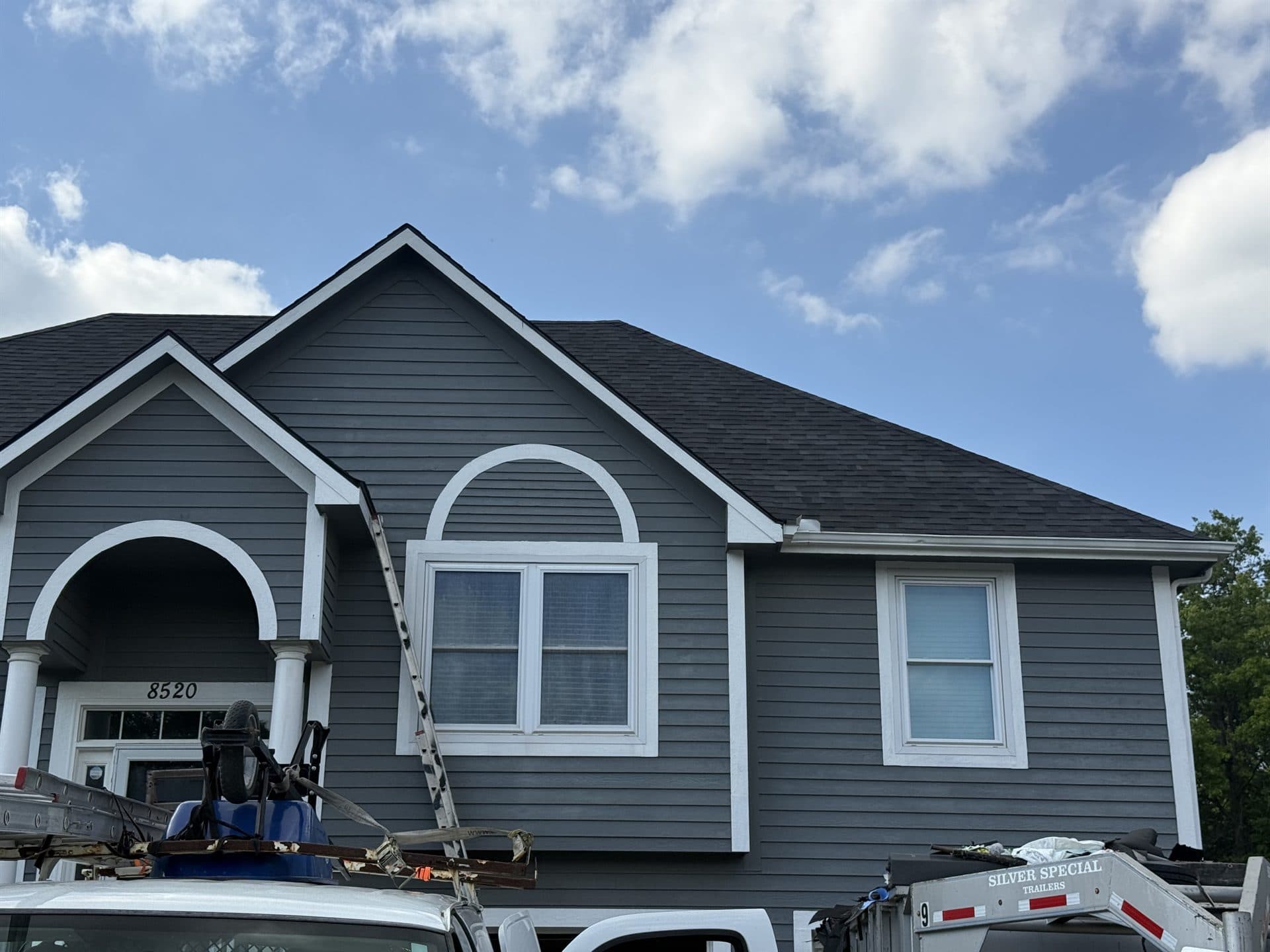 MCO Roofing crew replacing the roof on a blue two-story Kansas home