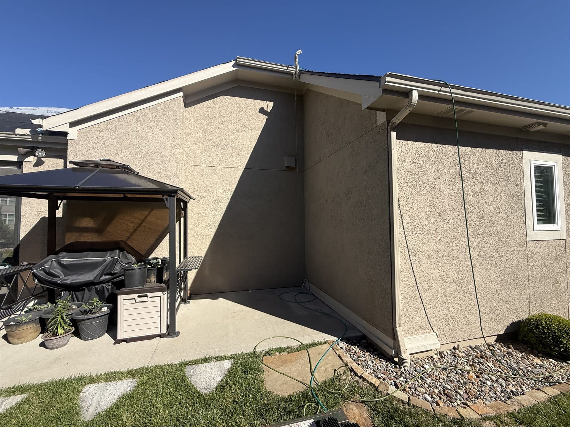 Completed roof replacement on a stucco home with a covered patio in Johnson County, KS